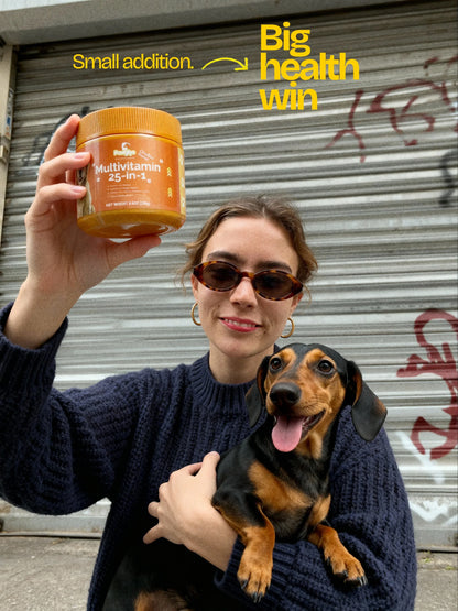 Woman holding Pawglys supplements multivitamin jar and dachshund dog outdoors, urban background